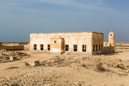 Ruined ancient old Arab pearling and fishing town Al Jumail, Qatar. The desert at coast of Persian Gulf. Abandoned mosque with minaret. Deserted village. Pile of stonesの写真素材