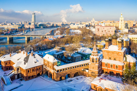Moscow, Russia - 29 Dec 2018: Winter view of Moskva river, Novospasskiy Bridge, and skyscrapers on a sunny morning. Krutitsy Metochion. Ice, snow on roofs and streets. White Christmas, New Year's eveのeditorial素材