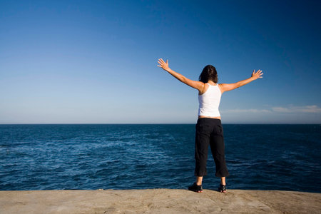 young girl meditating in front of ocean - freedom concept