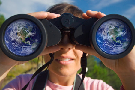 young woman with binoculars with the earth globe reflected in the lensの写真素材