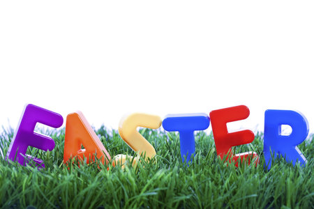 Easter word made with plastic letters on green grass - isolated on white background