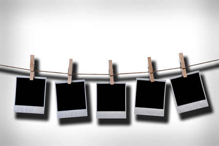 Empty disposable photo frames hanging in rope agains grunge white wallの写真素材