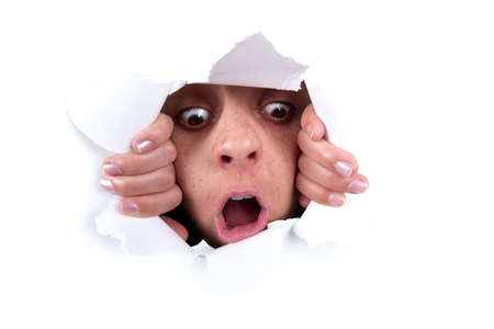 woman peeking behind white wall holeの写真素材