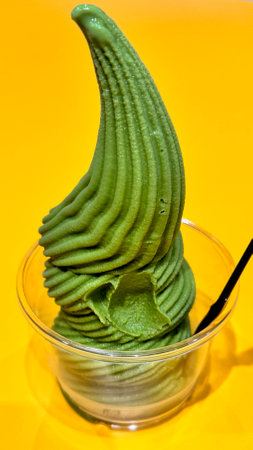 Green ice cream in a glass on a yellow background, close-upの写真素材
