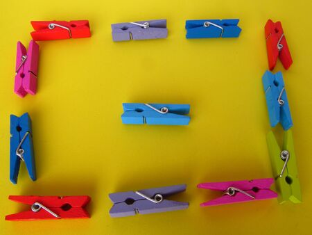 Clipper for hanging clothes on a rope. A multi-colored wooden decorative clip on a yellow background.の写真素材