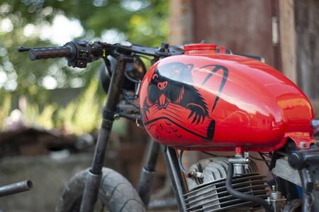 Refurbished retro moto bike is red in color with a beaver stick on a gas tank.の写真素材