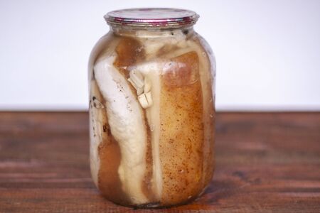 Salted pieces of lard with meat are closed in glass jars, close-up on a white backgroundの写真素材