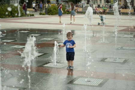 Ukraine, Uman, the territory of the Unity. 07.15.2019. People walking among the place in summer with fountains and enjoying running in water with bare feet making the splashes.のeditorial素材
