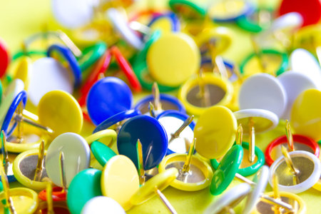 Stationery colorful buttons on yellow background. Carnations for training. Attaching paper.