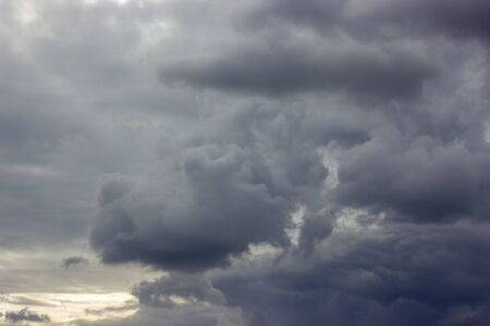 Dark heavy clouds. Rain clouds. Time before the rain. There are bright gaps behind the clouds. Background with free space and empty place.の写真素材