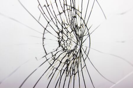 Cracked glass on white background texture. Broken glass. Cracks from impact or shot.の写真素材