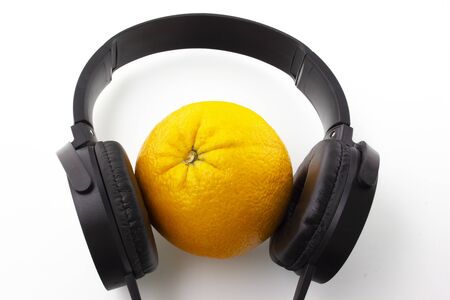 Orange in black headphones on a white background.の写真素材