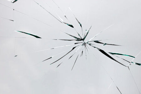 Broken window with cracks from impact or shot. Texture of cracks and chips on car windshield,...
