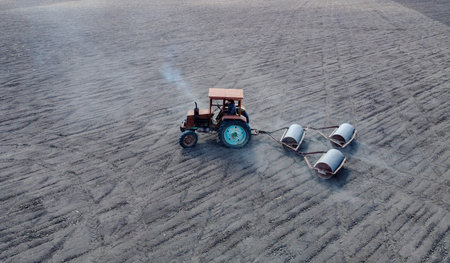 An old tractor that carries trailed roller blades to sow crops. Drought and dust rising from the air...