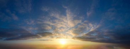 Sunset sky panorama with clouds and orange glow.