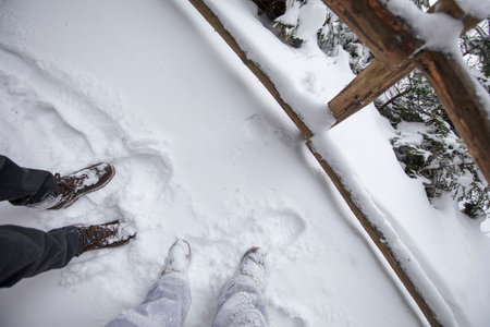 Legs of two people in the snow, shoes in a snowy path.
