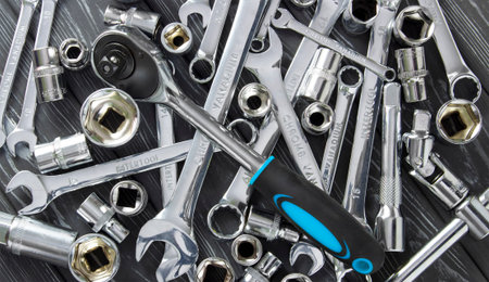 Wrenches on a wooden background. Rattle with a blue handle.