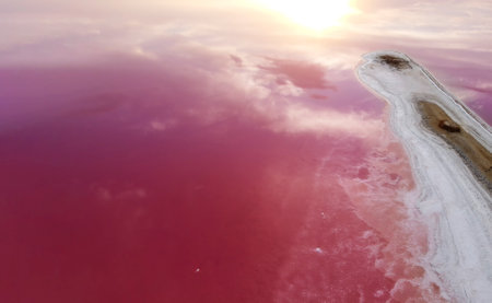 Beautiful pink water in the lake and a dramatic sky and the rising sun.の写真素材