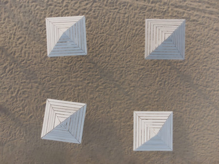 4 wooden white umbrellas on the beach, top view on the beach shading fungi for vacationers