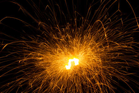 Close-up short exposure photo of a single burning sparkler, producing lots of pink bright hot sparksの写真素材