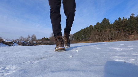 Mens shoes close up, steps on the snow time lapse shooting on a winter sunny day outdoors.