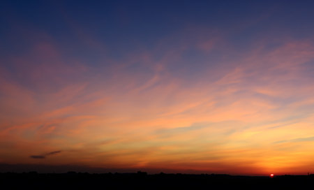 The beautiful sky at sunrise paints the horizon with a captivating orange light gradientの素材
