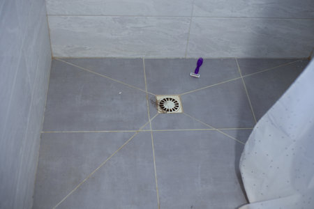 Hair in the shower sink and razor on the floor. Clogged sink after hairの写真素材