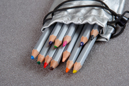 Colored pencils in a silver case on a gray background