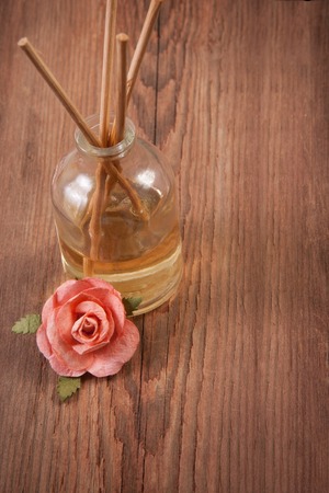 Fragrance sticks or Scent diffuser with rose flowers on wooden backgroundの写真素材