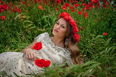 Lovely happy brunette woman, sitting in the poppy flower              の写真素材