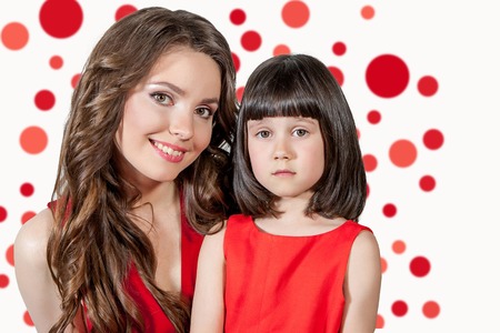 Beauty Portrait. mother and daughter in red dress. Beautiful lady make upの写真素材