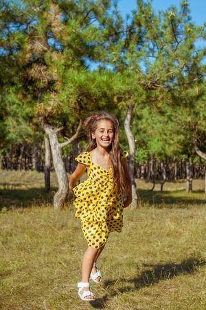 Rejoicing happy little girl in flying motion smiling full of joy and vitality in summer or spring forest.の写真素材