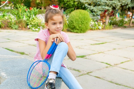 sad pensive cute 8 years old girl with racket outdoors. Looking away.の写真素材