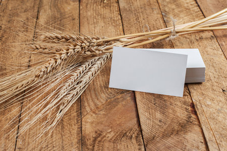 Photo of business cards. Template for branding identity. For graphic designers presentations and portfolios. With wheat spikelets on wooden background. Subject agronomist, agricultureの写真素材