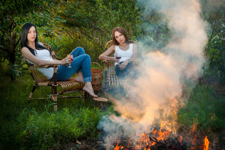 summer holidays and vacation - girls with red wine glasses near bonfireの写真素材