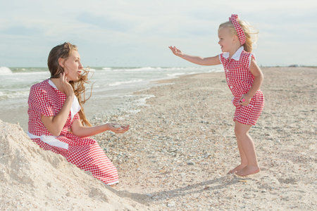 Happy family. Young happy beautiful  mother and her daughter  having fun on the beach. Positive...