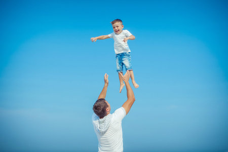Happy family. Father throws up child in the sky, on sunny day. Father and little son on the beach....