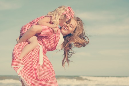 Happy family. Young beautiful  mother and her daughter  having fun on the beach. Positive human emotions, feelings. Retro tonedの写真素材