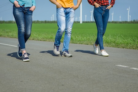 Young hipster friends on road. Two girls and a guy travel hitchhikers. Legsの写真素材