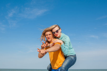 Happy young joyful guy and girl having fun on the beach, laughing together. During summer holidays vacation on sea. Beautiful energetic couple friends adolescents.の写真素材