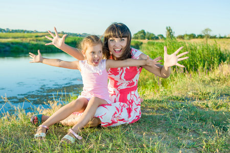 Mother and her daughter laughing and having fun outdoor. Happy family. Positive human emotions, feelings, joy. On bank of the riverの写真素材