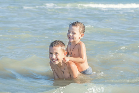 Happy Children - two boys, brothers having fun on the beach. Swimming in the sea. Positive human...
