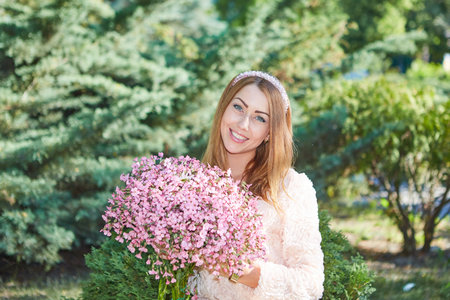 Beautiful girl With bouquet of flowers.  in the garden, pleasure sunlight and warmth. Beauty model woman face.の写真素材