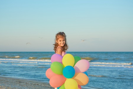 Happy little Girl on the beach with balloons. Positive human emotions, feelings.の写真素材