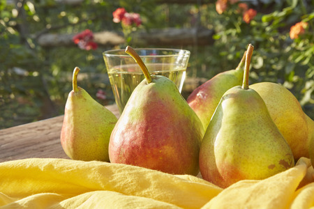 Pears and cider in a glass. Ripe fresh Pears, on wooden table, on nature backgroundの写真素材