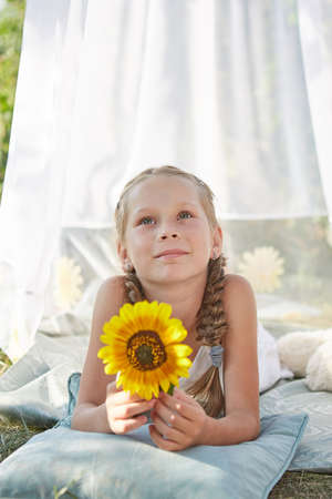 Little girl in  white chiffon tent with sunflower. Childhood, tenderness, beautyの写真素材