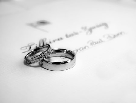 A pair of platinum wedding bands lying on Malta civil wedding certificateの写真素材
