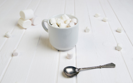 Minimalistic composition with marshmallow, cup and spoon on white tableの写真素材