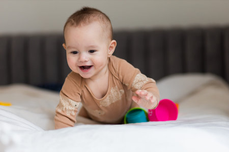 baby up to a year old, lying on the bed among toys