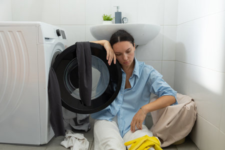A tired housewife sits by the dirty laundry. Domestic routine and womens work.の写真素材